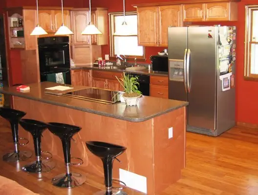 Finished kitchen remodel by C.B.E. Construction with maple cabinets, a dark counter and an island with bar stools