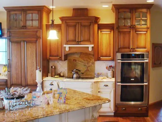 Finished kitchen remodel with warm wood cabinetry, a granite island and glass front upper cabinets