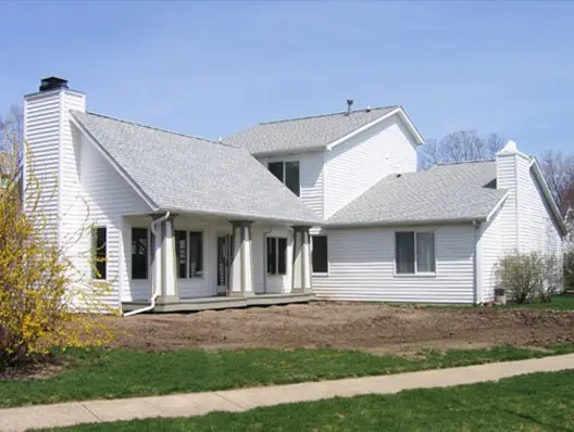 Finished white two storey home built by C.B.E. Construction under a blue spring sky