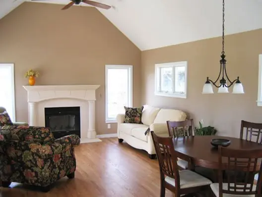 Vaulted great room with a white fireplace mantel, transom windows and hardwood floor in a C.B.E. Construction home