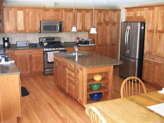 Finished kitchen remodel with honey oak cabinetry, a granite island and open shelving